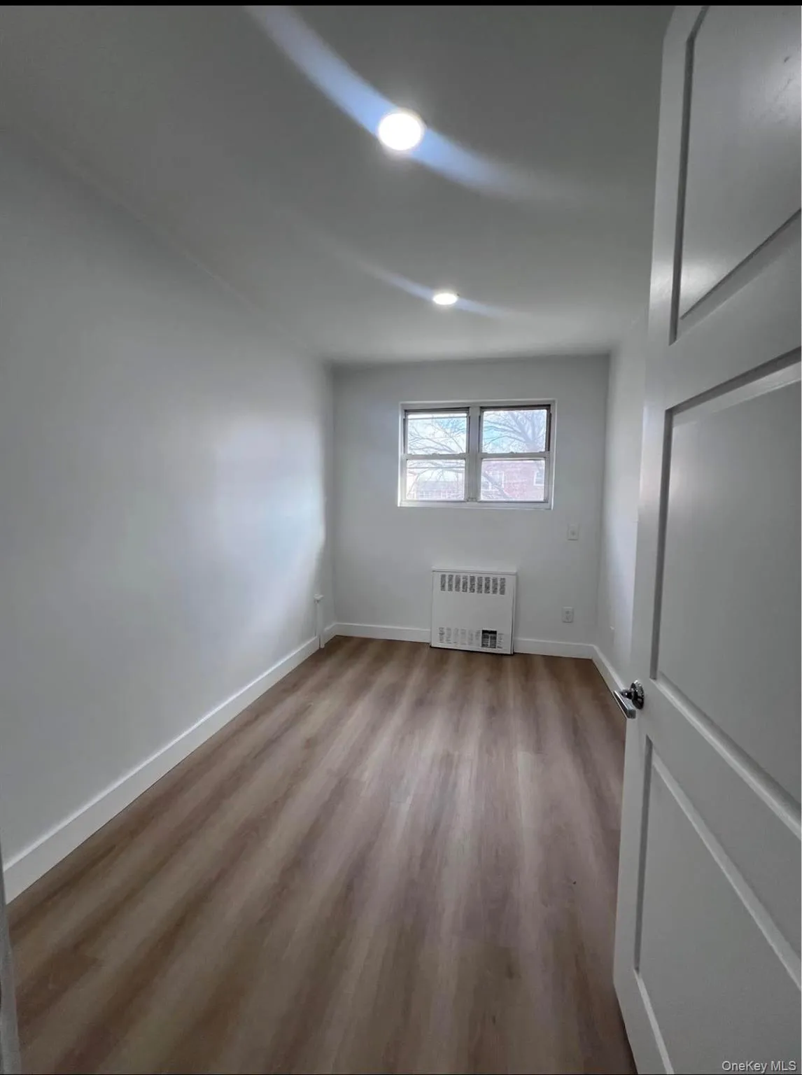 Empty room with light wood-type flooring and radiator Empty room with light wood-type flooring and radiator