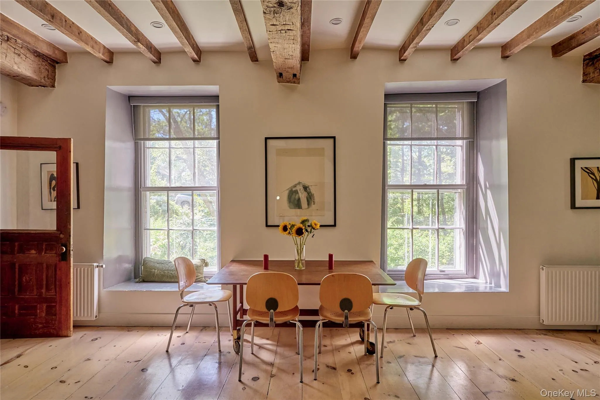 Dining area featuring radiator heating unit, beam ceiling, and hardwood / wood-style flooring Dining area featuring radiator heating unit, beam ceiling, and hardwood / wood-style flooring