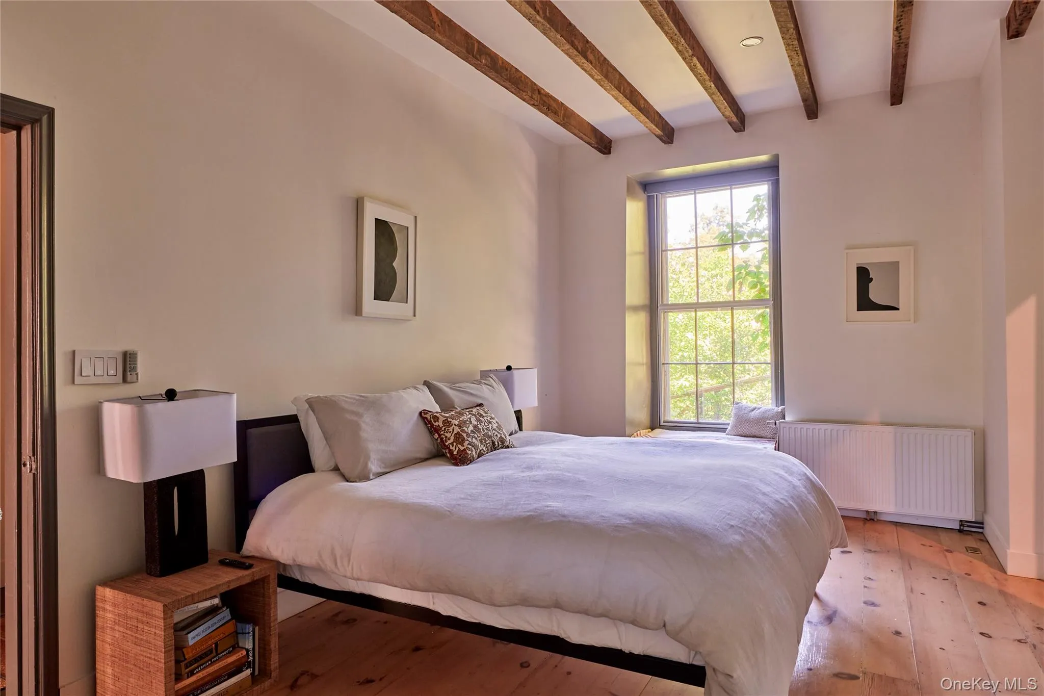 Bedroom featuring radiator, beam ceiling, and hardwood / wood-style flooring Bedroom featuring radiator, beam ceiling, and hardwood / wood-style flooring