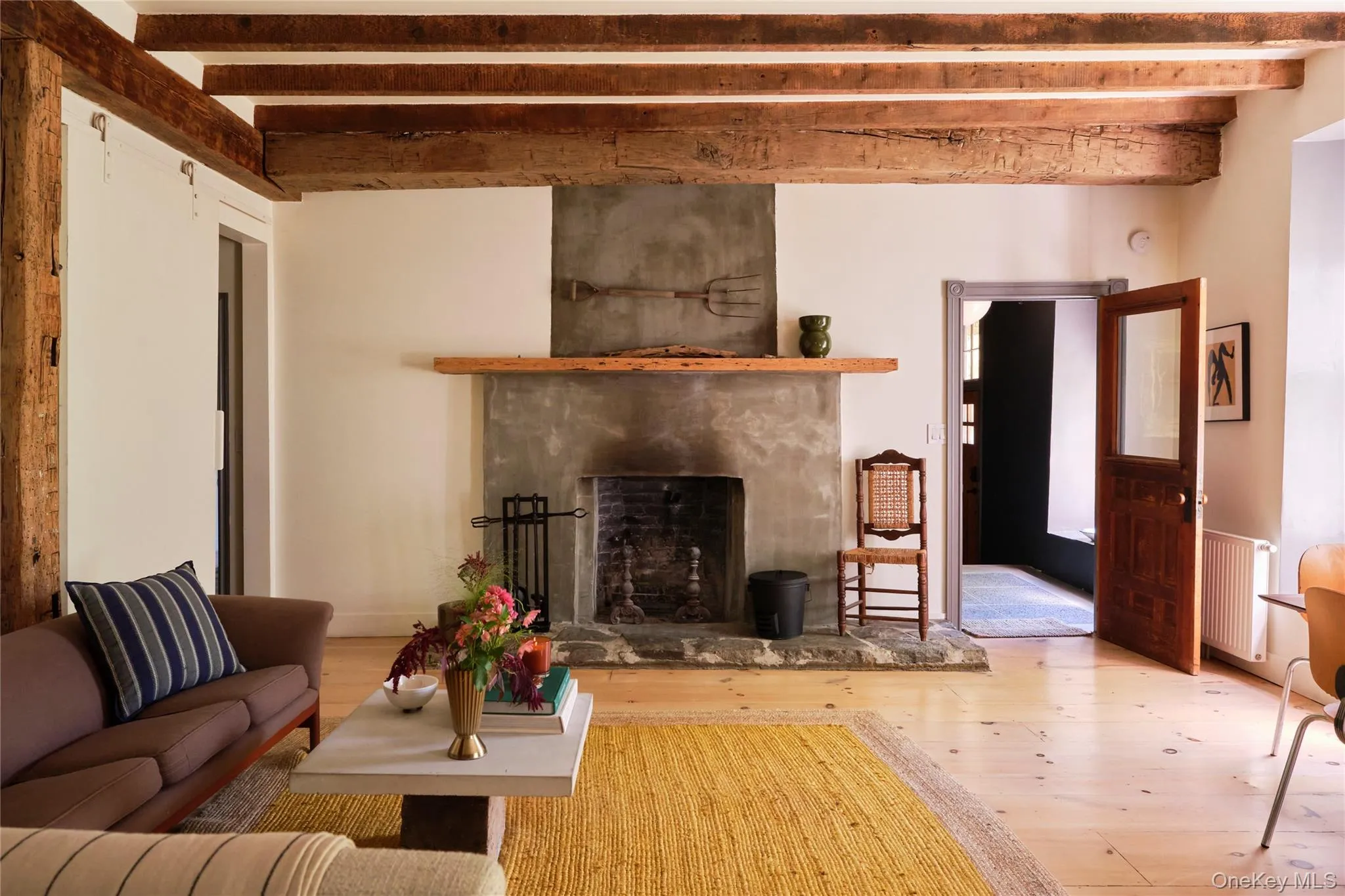 Living area with a premium fireplace, beamed ceiling, radiator, and hardwood / wood-style flooring Living area with a premium fireplace, beamed ceiling, radiator, and hardwood / wood-style flooring