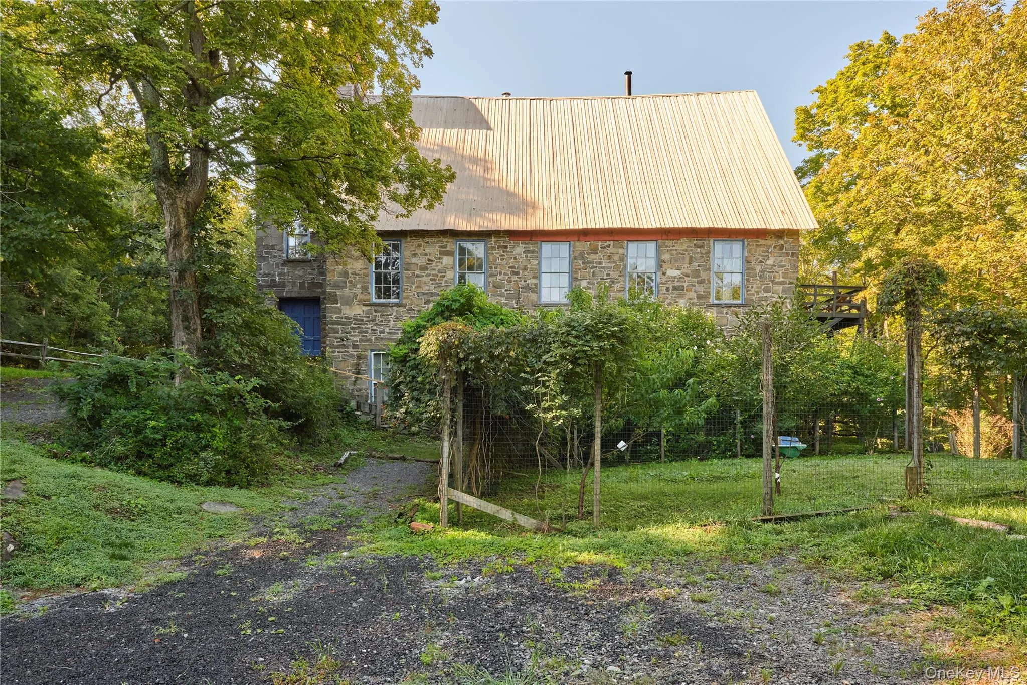 Back of house featuring stone siding and a metal roof Back of house featuring stone siding and a metal roof
