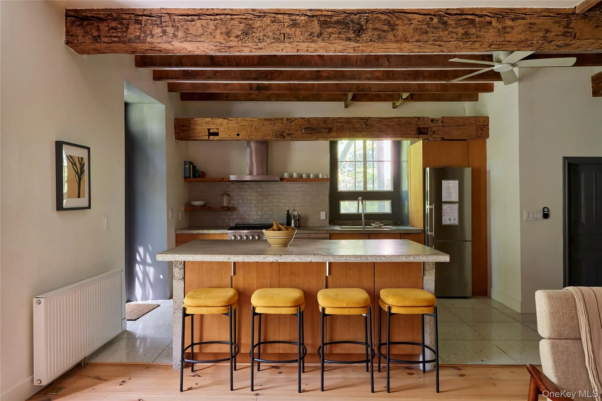 Kitchen with radiator heating unit, a kitchen breakfast bar, light countertops, stainless steel appliances, and beamed ceiling Kitchen with radiator heating unit, a kitchen breakfast bar, light countertops, stainless steel appliances, and beamed ceiling