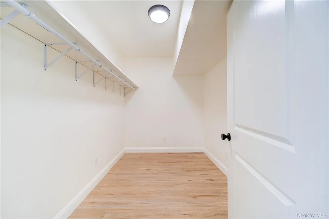 Walk in closet with light hardwood / wood-style floors Walk in closet with light hardwood / wood-style floors