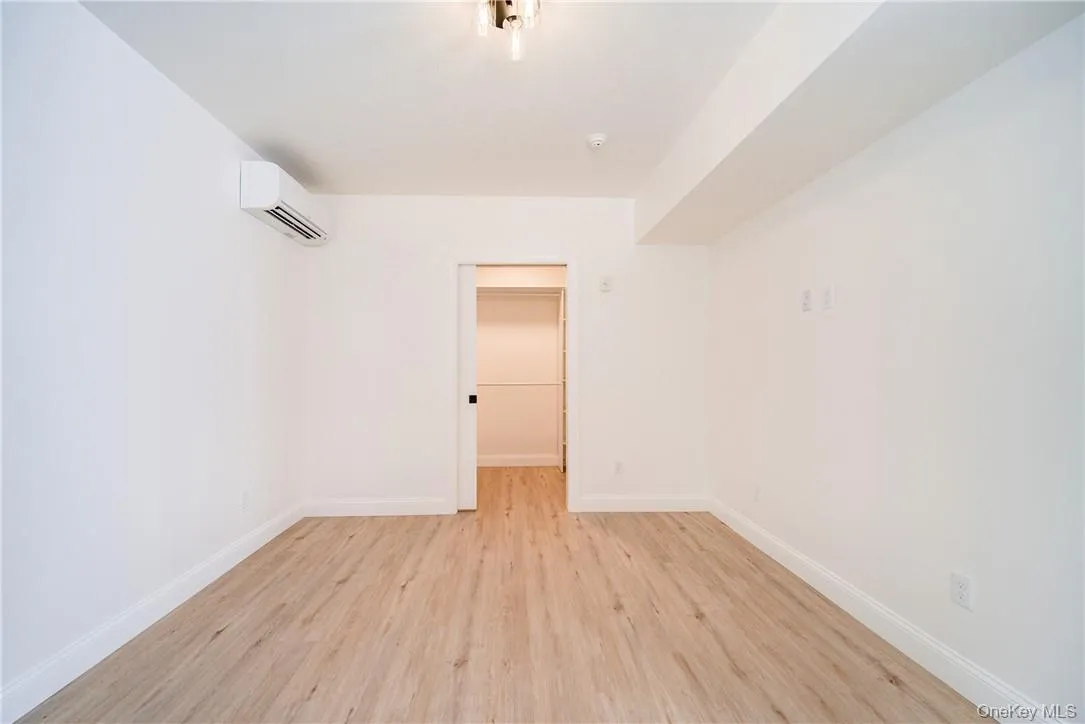 Empty room featuring a wall unit AC and light wood-type flooring Empty room featuring a wall unit AC and light wood-type flooring