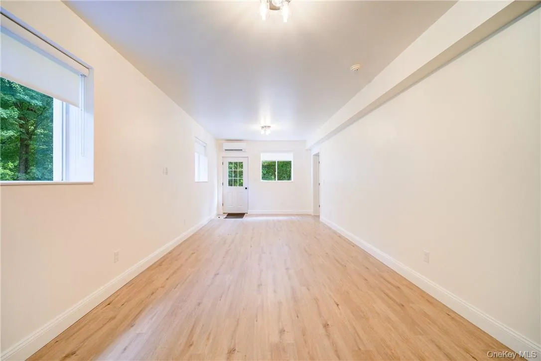 Unfurnished room with a wall mounted AC and light hardwood / wood-style floors Unfurnished room with a wall mounted AC and light hardwood / wood-style floors