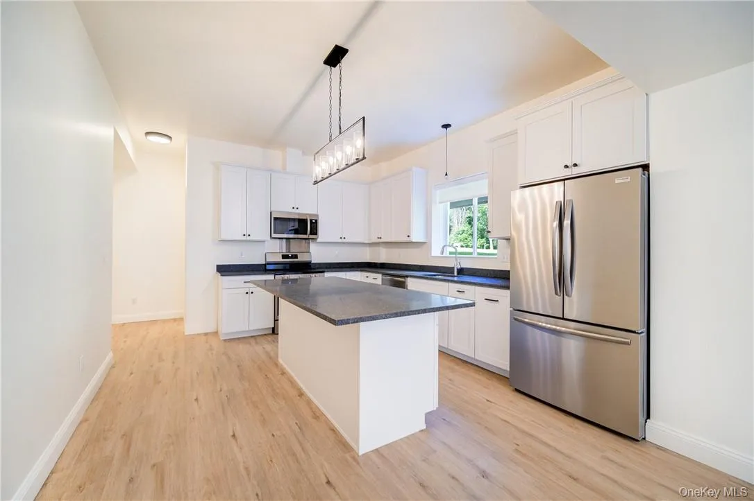 Kitchen with a center island, white cabinets, and stainless steel appliances Kitchen with a center island, white cabinets, and stainless steel appliances