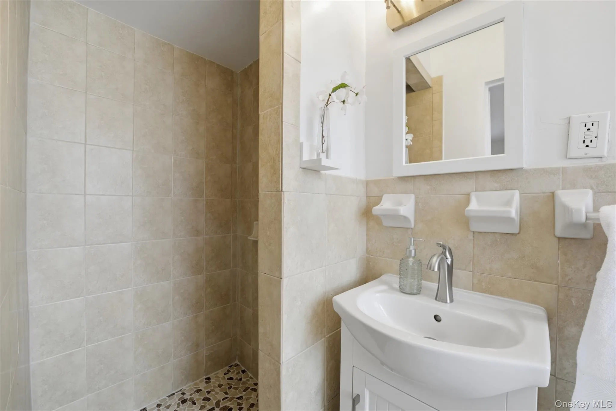 Primary bathroom featuring tiled walls and a stand-in shower. Primary bathroom featuring tiled walls and a stand-in shower.