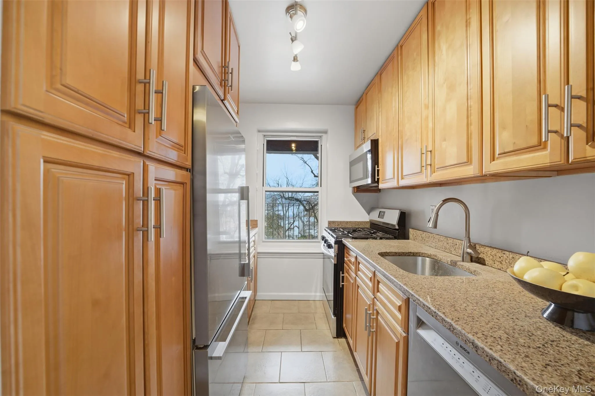 Kitchen featuring stainless steel appliances, wood cabinetry, light stone countertops, and a natural wood prep surface, with Hudson River views. Kitchen featuring stainless steel appliances, wood cabinetry, light stone countertops, and a natural wood prep surface, with Hudson River views.