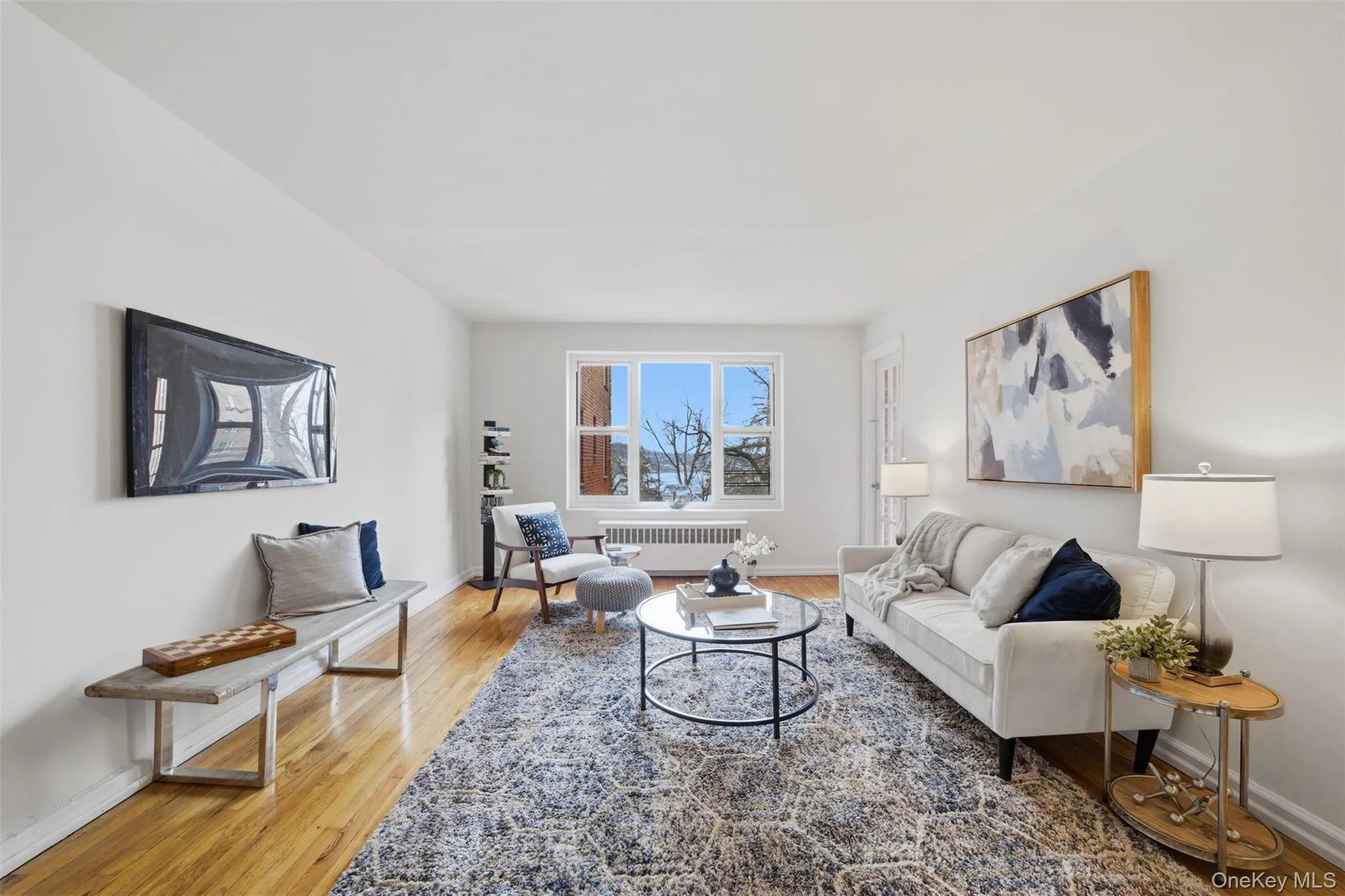 Bright living room with hardwood floors and seamless access to a private balcony showcasing Hudson River views. Bright living room with hardwood floors and seamless access to a private balcony showcasing Hudson River views.
