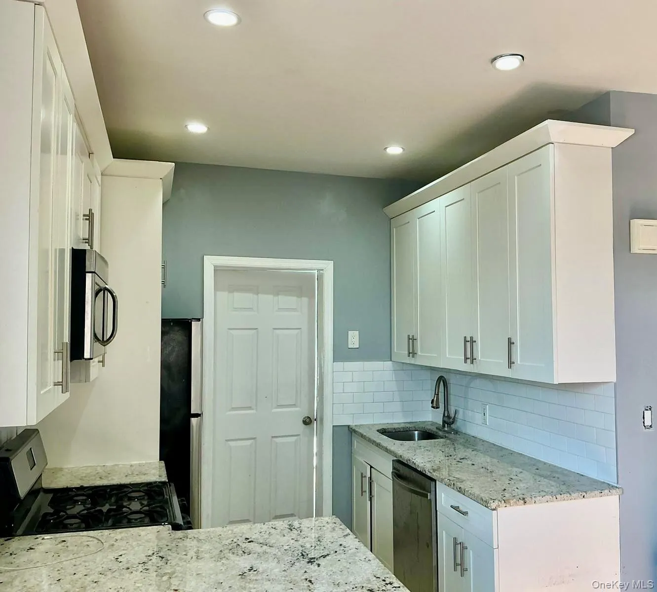 Kitchen featuring light stone countertops, white cabinetry, stainless steel appliances, backsplash, and recessed lighting Kitchen featuring light stone countertops, white cabinetry, stainless steel appliances, backsplash, and recessed lighting