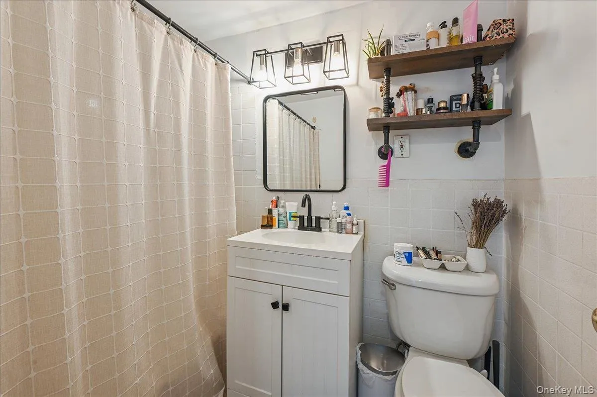 Full bath with vanity, tile walls, and curtained shower Full bath with vanity, tile walls, and curtained shower