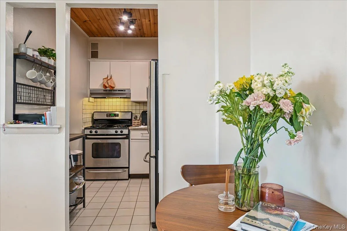 Kitchen with stainless steel appliances, wood ceiling, decorative backsplash, light tile patterned floors, and white cabinets Kitchen with stainless steel appliances, wood ceiling, decorative backsplash, light tile patterned floors, and white cabinets