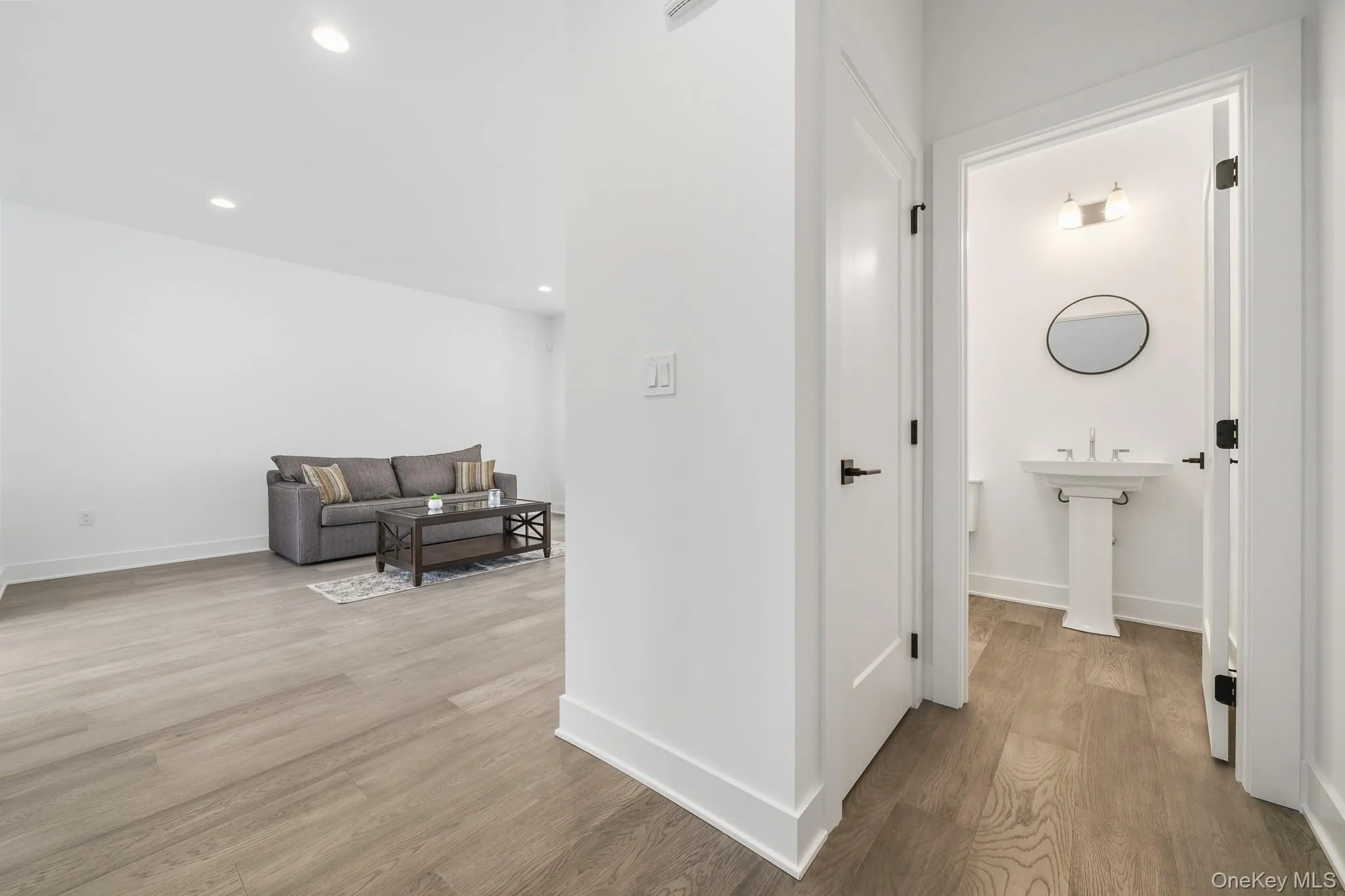 Hallway featuring half bath, light wood-style floors and recessed lighting Hallway featuring half bath, light wood-style floors and recessed lighting