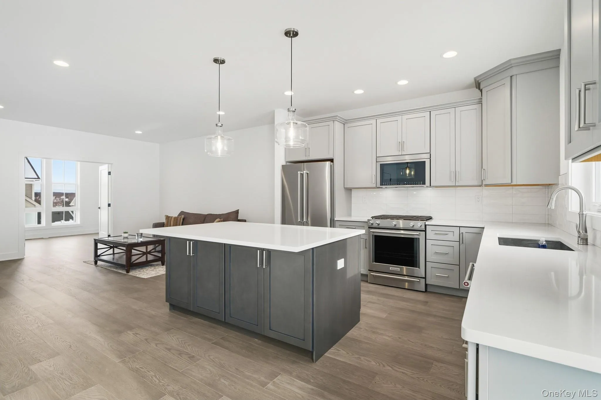 Kitchen featuring stainless steel appliances, pendant lighting, a kitchen island, dark wood-type flooring, and recessed lighting Kitchen featuring stainless steel appliances, pendant lighting, a kitchen island, dark wood-type flooring, and recessed lighting