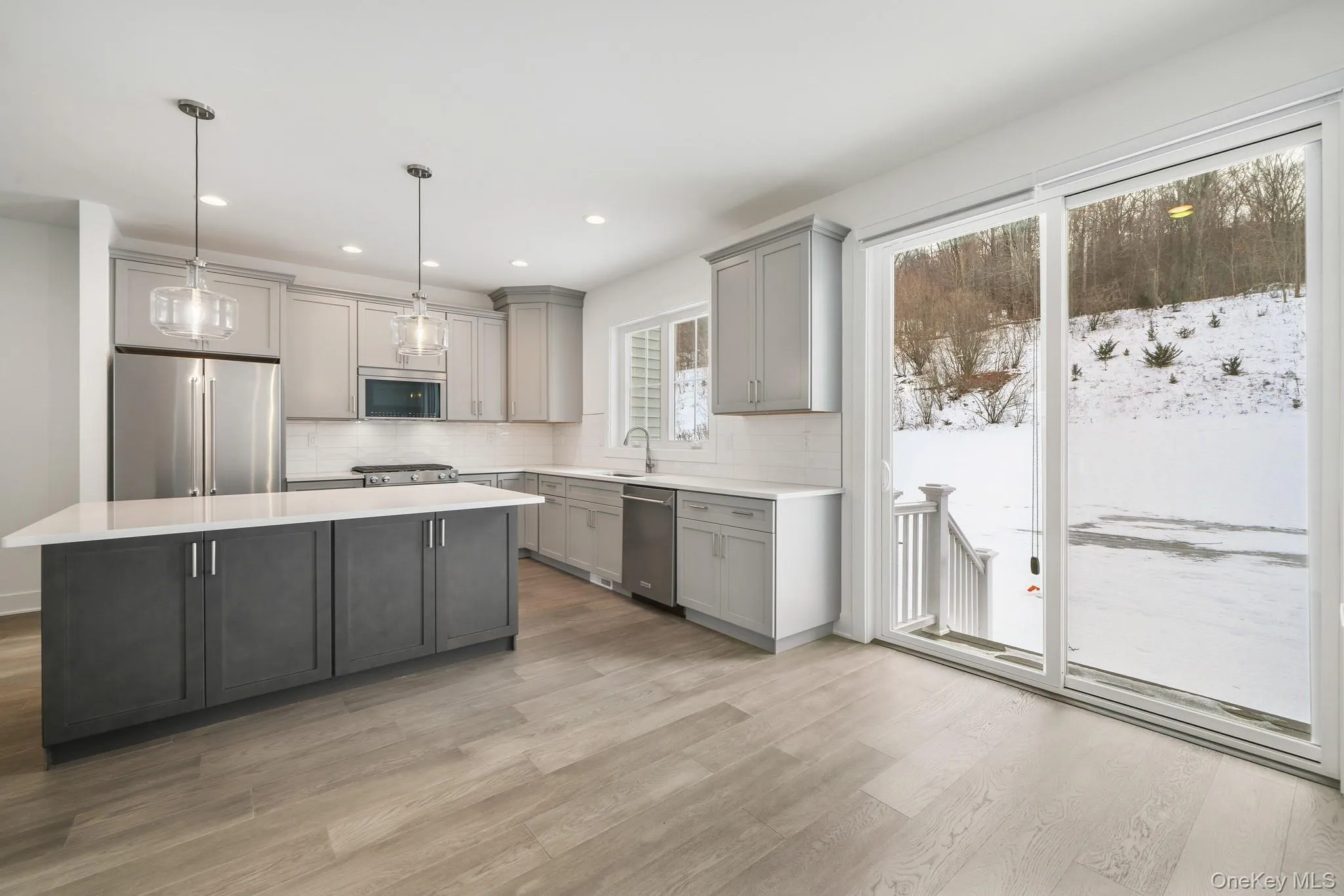 Kitchen with gray cabinets, stainless steel appliances, pendant lighting, light wood-style flooring, and recessed lighting Kitchen with gray cabinets, stainless steel appliances, pendant lighting, light wood-style flooring, and recessed lighting