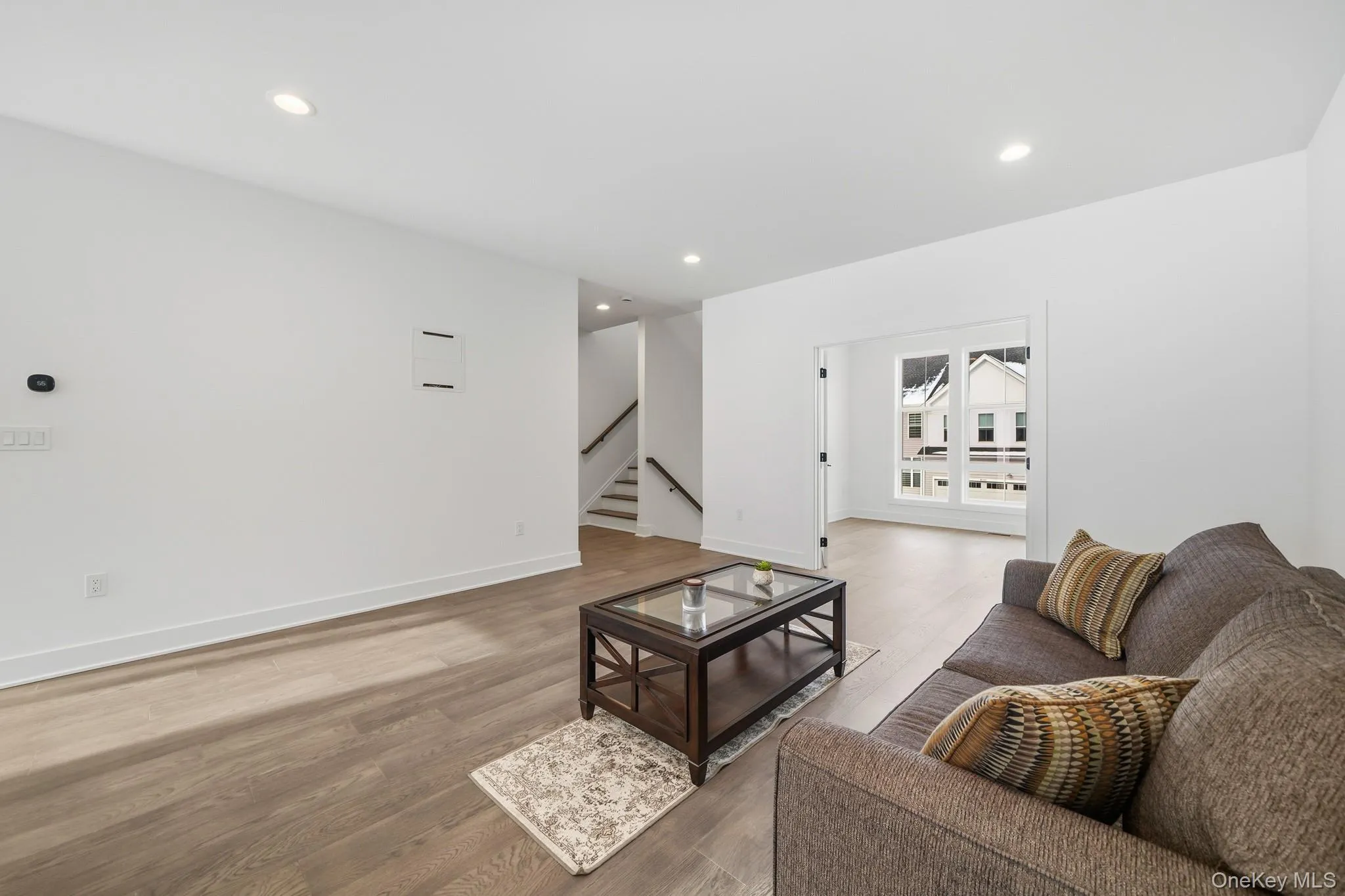 Living area featuring wood finished floors, recessed lighting, and stairway Living area featuring wood finished floors, recessed lighting, and stairway