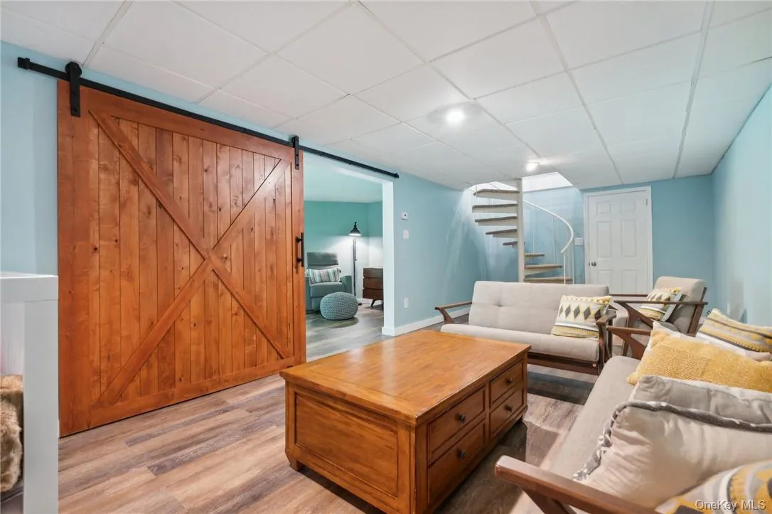 Living room featuring a barn door, hardwood / wood-style floors, and a drop ceiling Living room featuring a barn door, hardwood / wood-style floors, and a drop ceiling