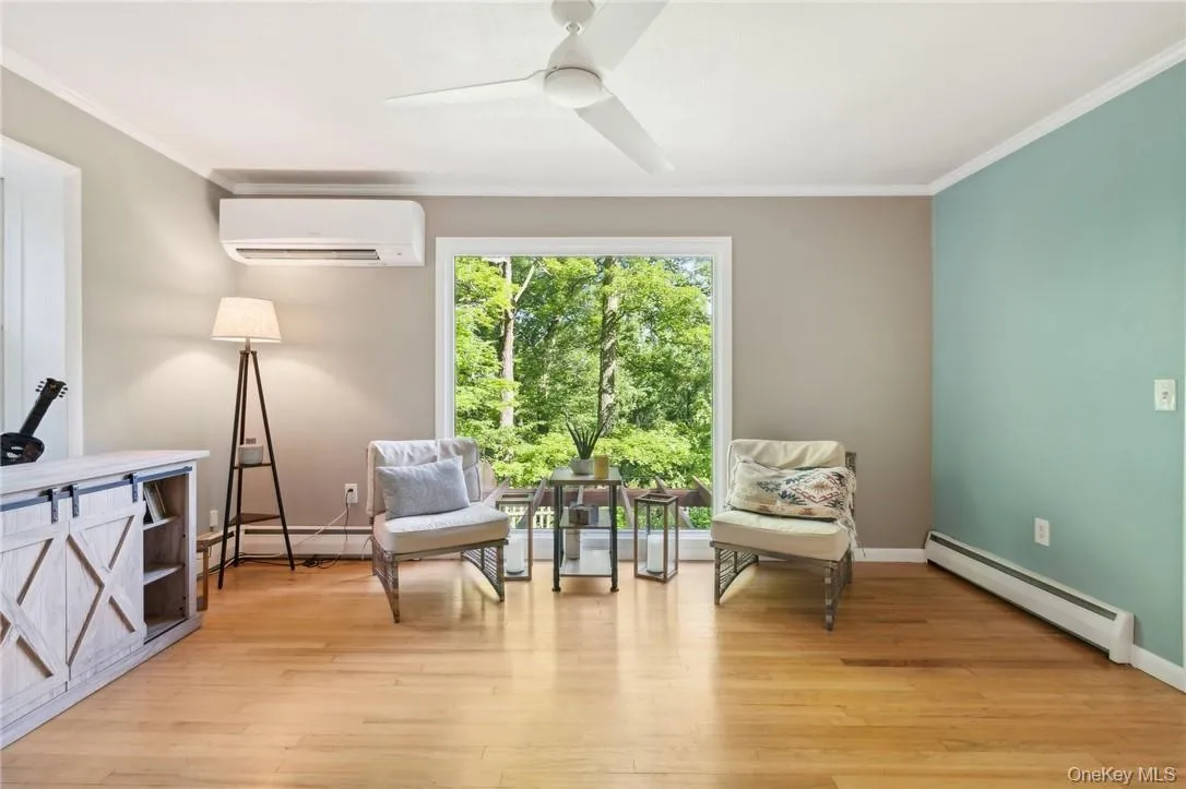 Sitting room with light hardwood / wood-style floors, baseboard heating, a wall unit AC, and ceiling fan Sitting room with light hardwood / wood-style floors, baseboard heating, a wall unit AC, and ceiling fan