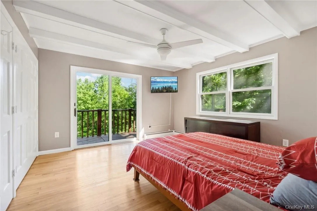 Bedroom featuring ceiling fan, beamed ceiling, baseboard heating, access to outside, and hardwood / wood-style flooring Bedroom featuring ceiling fan, beamed ceiling, baseboard heating, access to outside, and hardwood / wood-style flooring