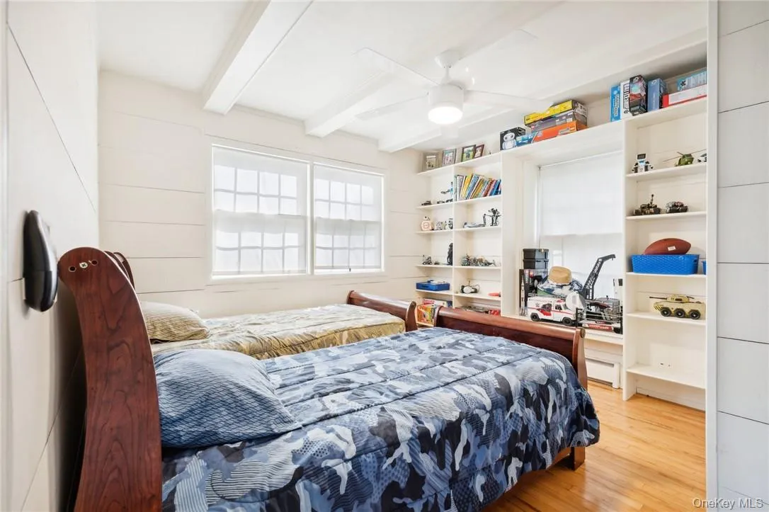 Bedroom featuring beam ceiling, ceiling fan, and light hardwood / wood-style floors Bedroom featuring beam ceiling, ceiling fan, and light hardwood / wood-style floors