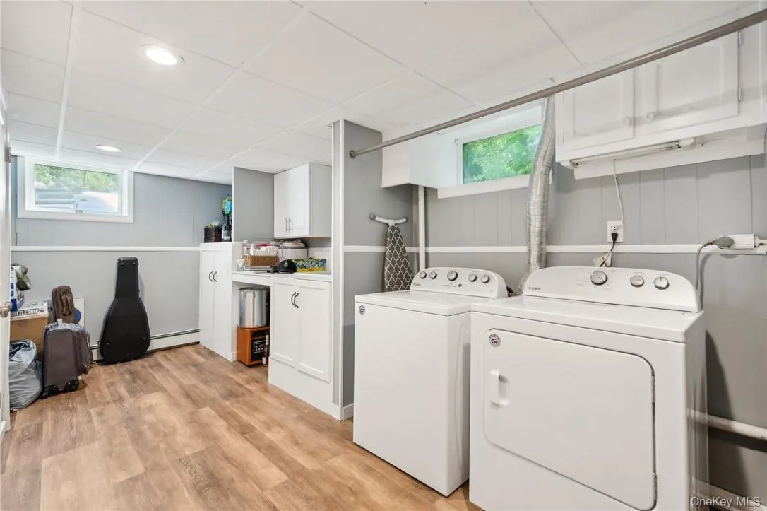 Washroom featuring a baseboard heating unit, light hardwood / wood-style flooring, and washer and clothes dryer Washroom featuring a baseboard heating unit, light hardwood / wood-style flooring, and washer and clothes dryer