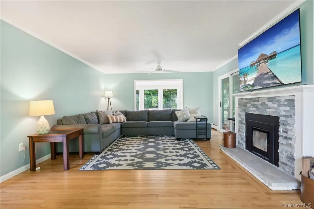 Living room with ceiling fan, ornamental molding, a fireplace, and light wood-type flooring Living room with ceiling fan, ornamental molding, a fireplace, and light wood-type flooring