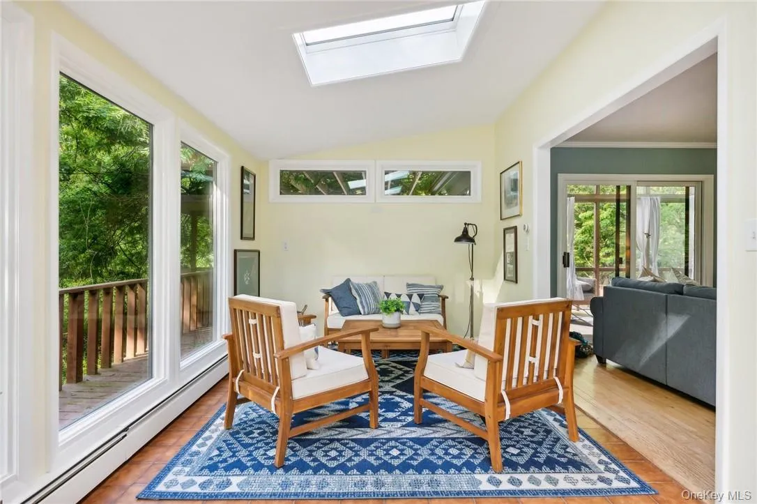Sunroom / solarium featuring a baseboard radiator and lofted ceiling with skylight Sunroom / solarium featuring a baseboard radiator and lofted ceiling with skylight