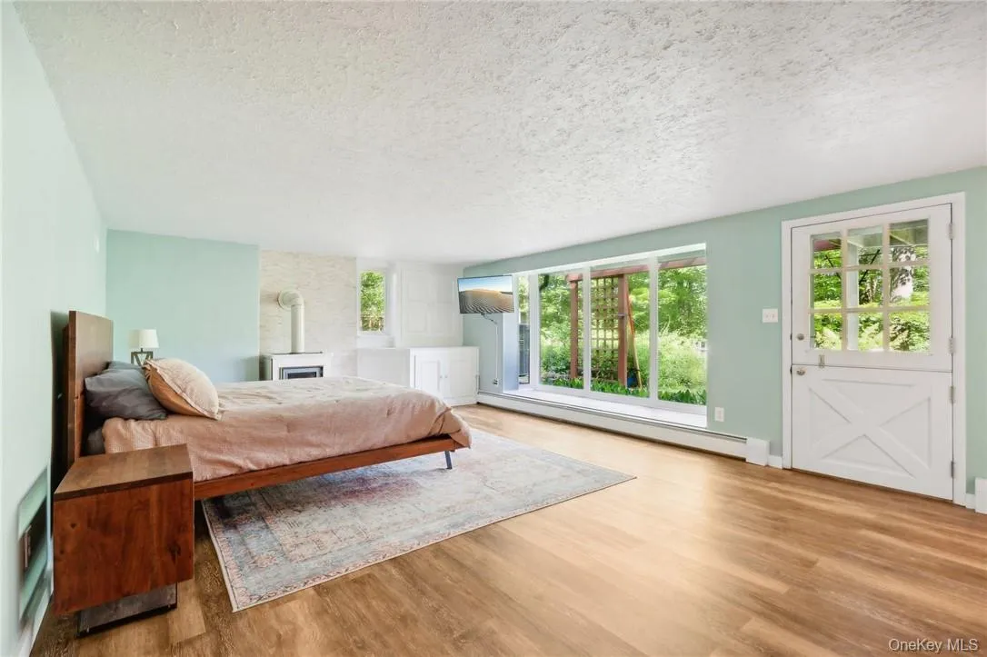 Bedroom with a baseboard heating unit, light hardwood / wood-style floors, and a textured ceiling Bedroom with a baseboard heating unit, light hardwood / wood-style floors, and a textured ceiling