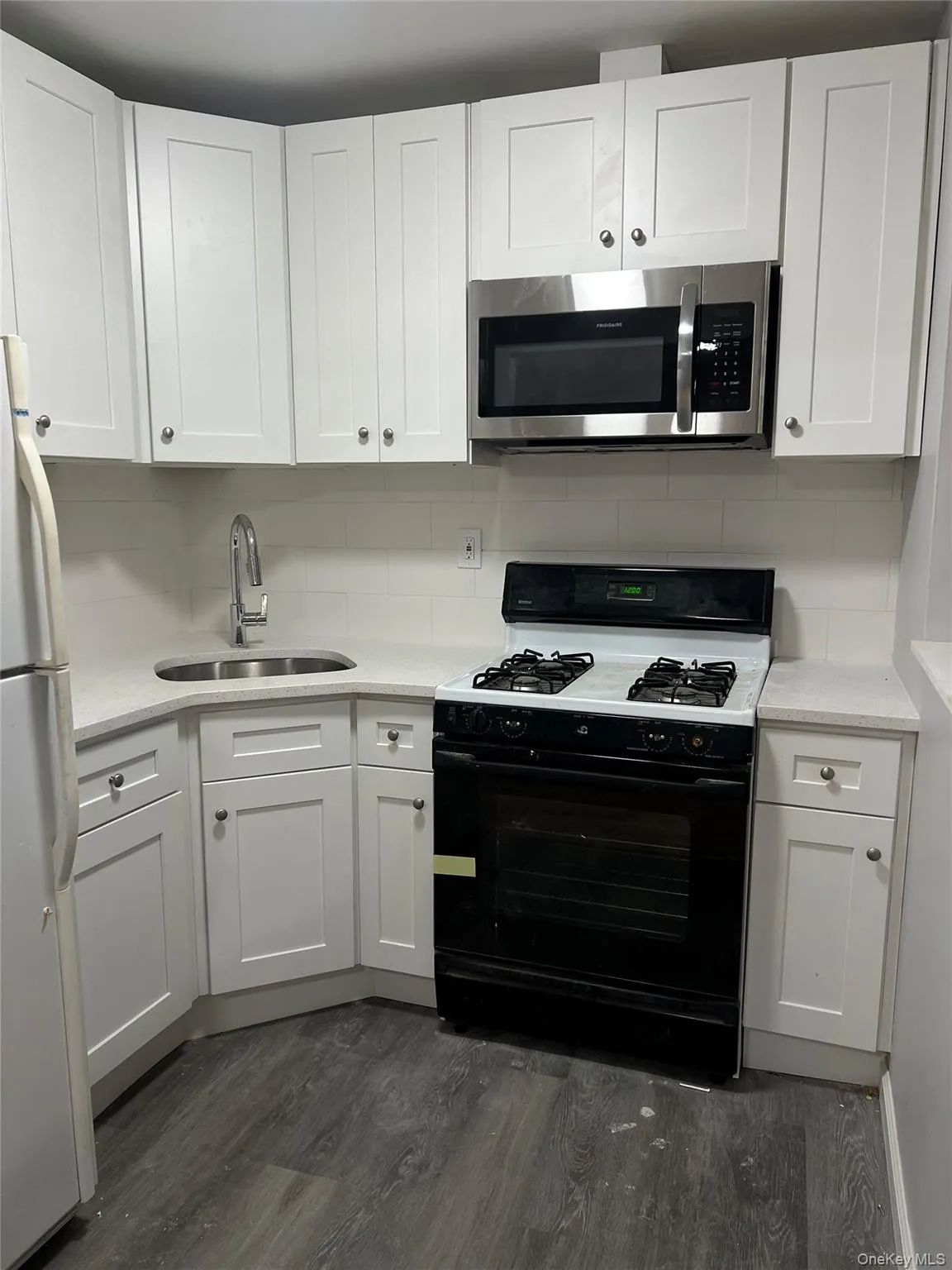 Modernized kitchen equipped with crisp white Shaker-style cabinetry, sleek stone countertops, and a stylish subway tile backsplash. Stainless steel appliances—including a built-in microwave and gas range—complete this functional and bright culinary space. Modernized kitchen equipped with crisp white Shaker-style cabinetry, sleek stone countertops, and a stylish subway tile backsplash. Stainless steel appliances—including a built-in microwave and gas range—complete this functional and bright culinary space.