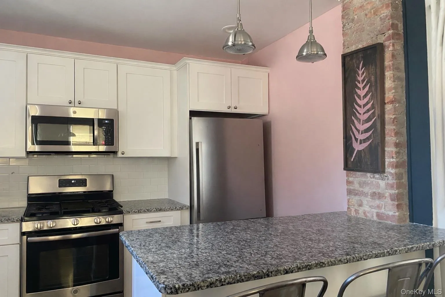 Kitchen with stainless steel appliances, white cabinetry, a peninsula, hanging light fixtures, and tasteful backsplash Kitchen with stainless steel appliances, white cabinetry, a peninsula, hanging light fixtures, and tasteful backsplash
