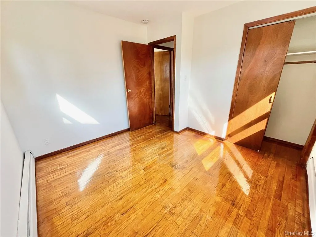 Unfurnished bedroom with a closet, light hardwood / wood-style floors, and a baseboard radiator Unfurnished bedroom with a closet, light hardwood / wood-style floors, and a baseboard radiator