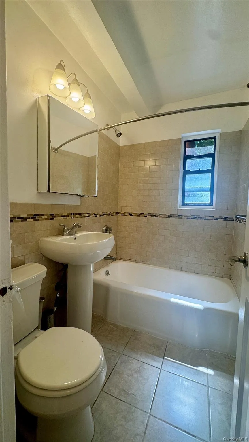 Bathroom featuring bathing tub / shower combination, tile walls, and tile patterned floors Bathroom featuring bathing tub / shower combination, tile walls, and tile patterned floors
