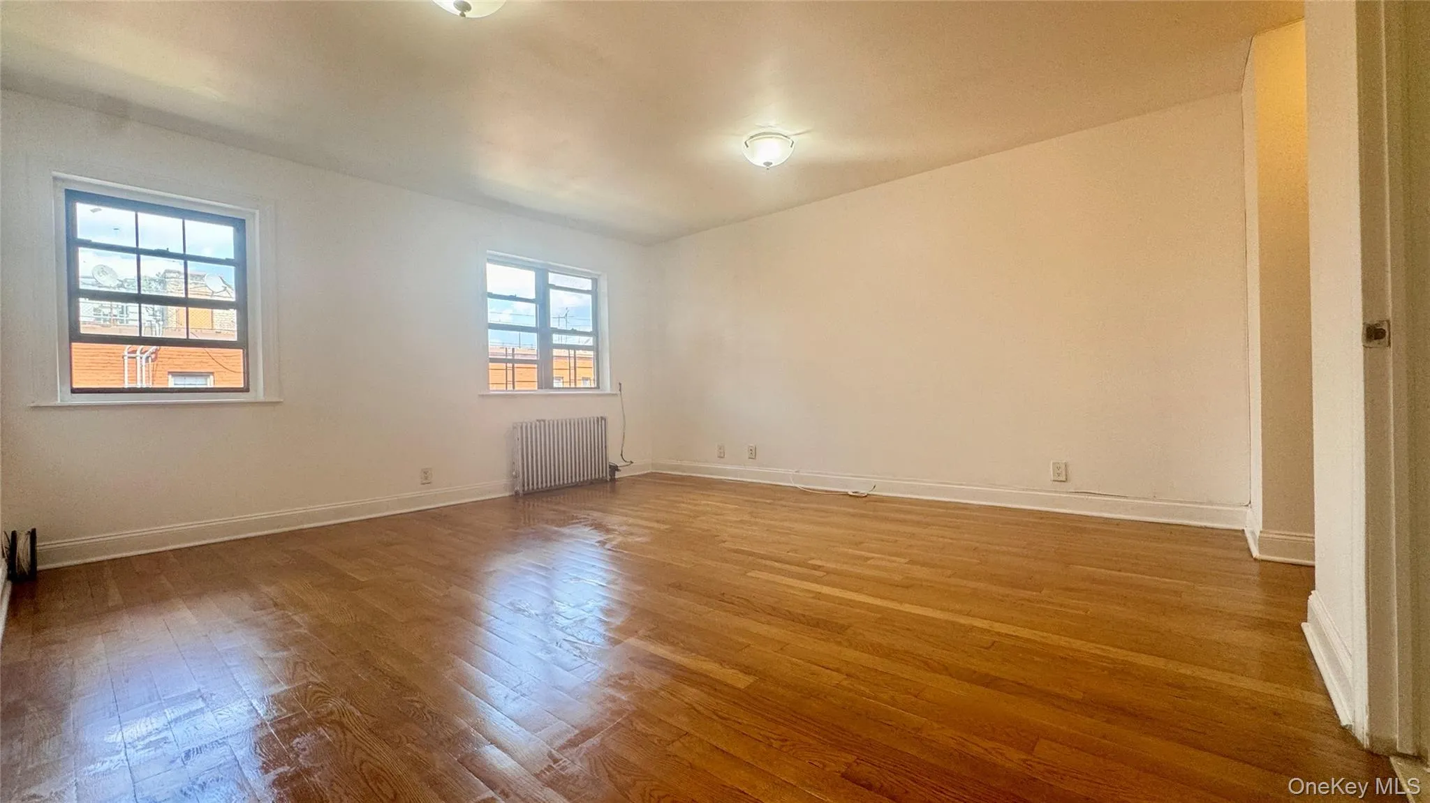 Spare room featuring radiator heating unit and wood finished floors Spare room featuring radiator heating unit and wood finished floors