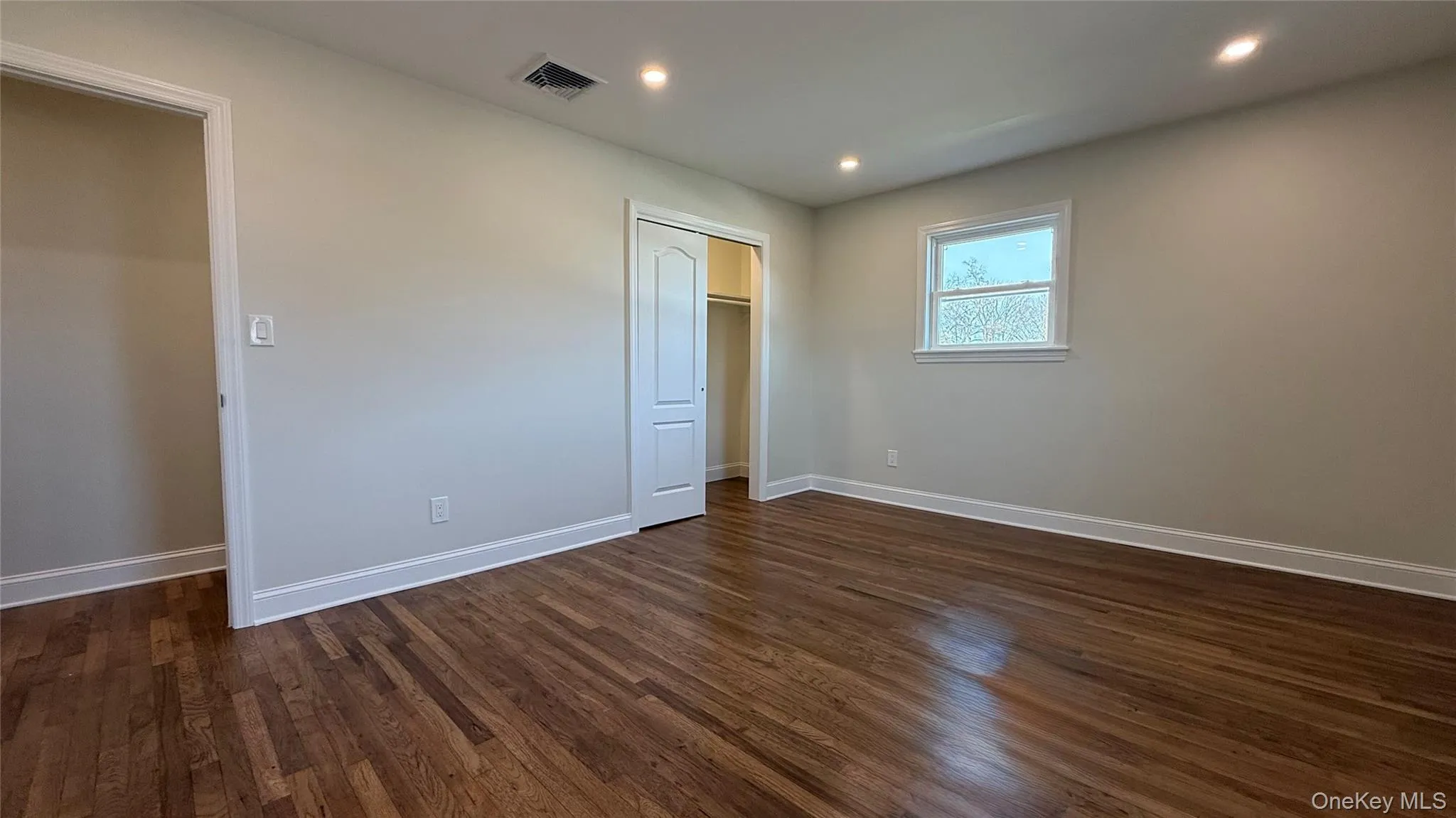 Primary bedroom featuring recessed lighting, dark wood-style flooring, and a closet Primary bedroom featuring recessed lighting, dark wood-style flooring, and a closet