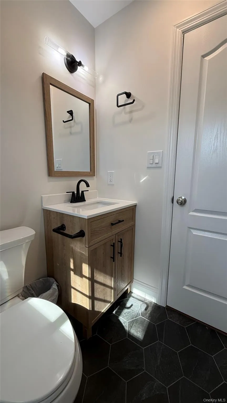 Full bathroom on second floor with vanity and dark tile patterned flooring Full bathroom on second floor with vanity and dark tile patterned flooring