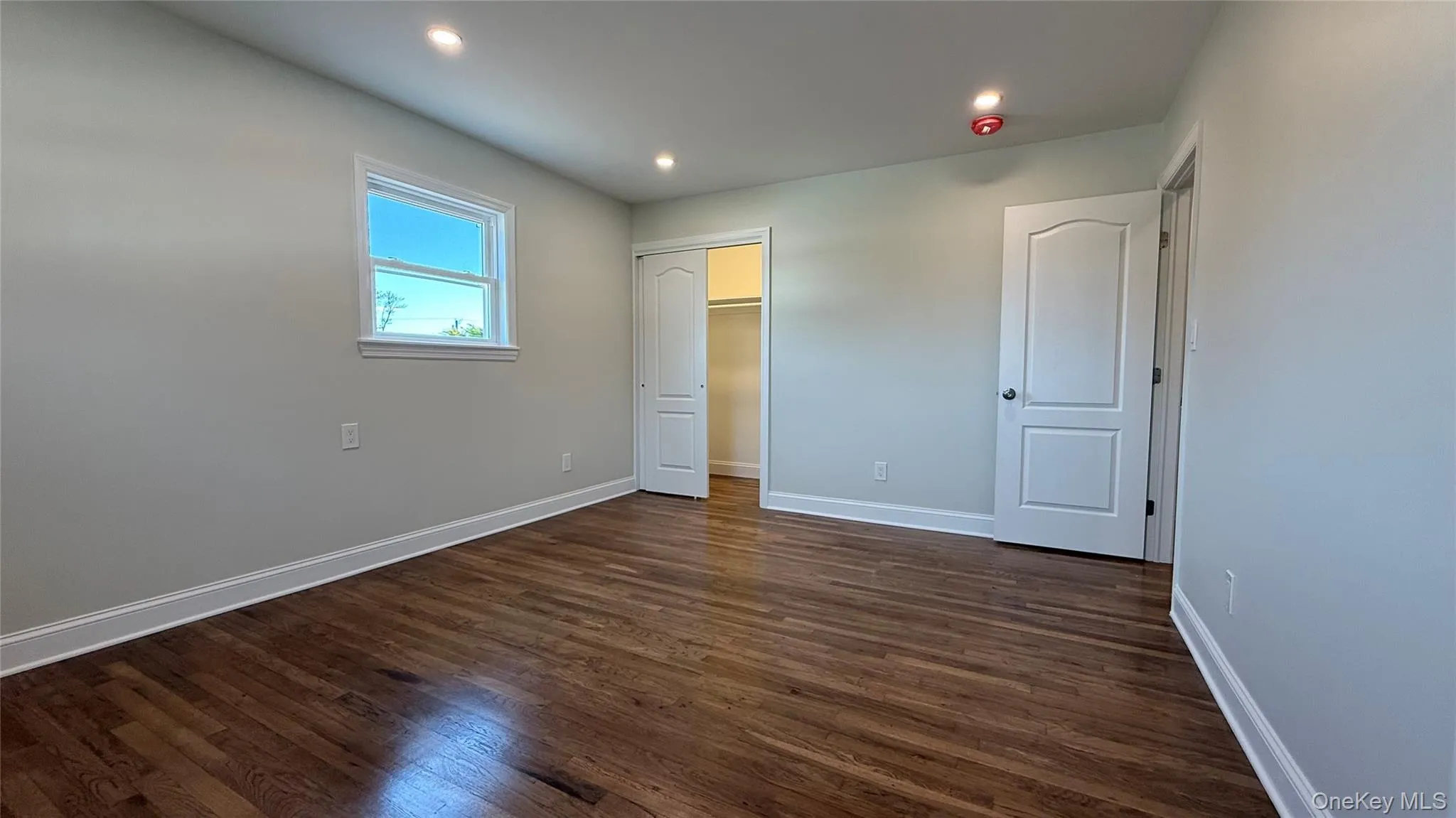 Primary bedroom featuring recessed lighting, dark wood-style flooring, and a closet on each side of the room Primary bedroom featuring recessed lighting, dark wood-style flooring, and a closet on each side of the room