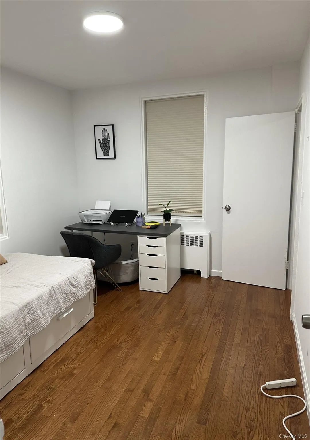 Bedroom featuring radiator heating unit and wood finished floors Bedroom featuring radiator heating unit and wood finished floors