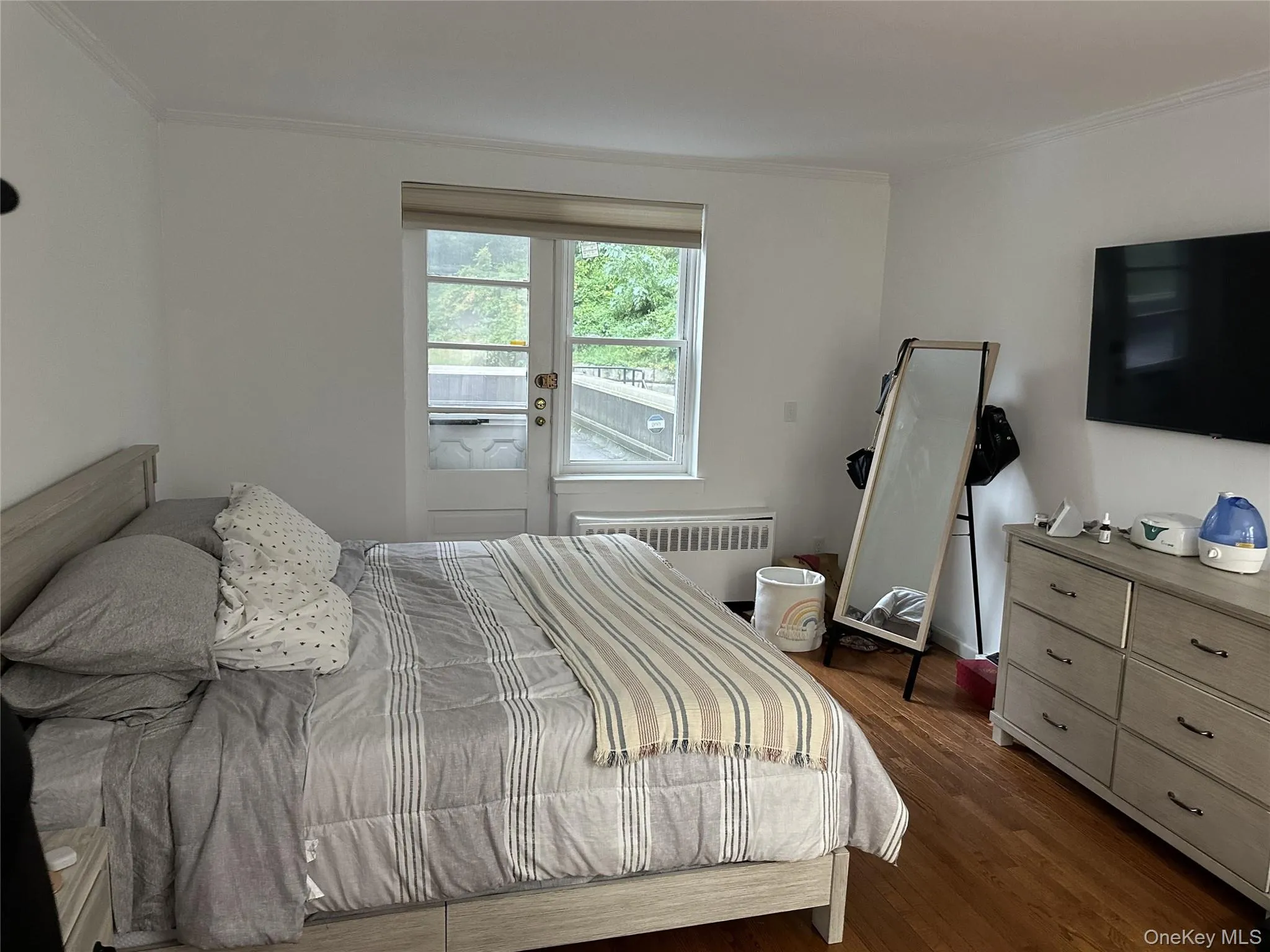 Bedroom with ornamental molding, radiator, and dark wood-style flooring Bedroom with ornamental molding, radiator, and dark wood-style flooring