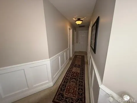 Hall featuring a decorative wall and wainscoting Hall featuring a decorative wall and wainscoting