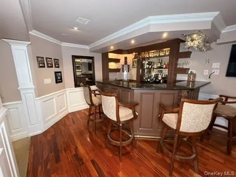 Bar area with crown molding, a wainscoted wall, and a decorative wall Bar area with crown molding, a wainscoted wall, and a decorative wall