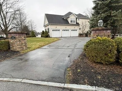 View of side of home with asphalt driveway, a front yard, and a garage View of side of home with asphalt driveway, a front yard, and a garage