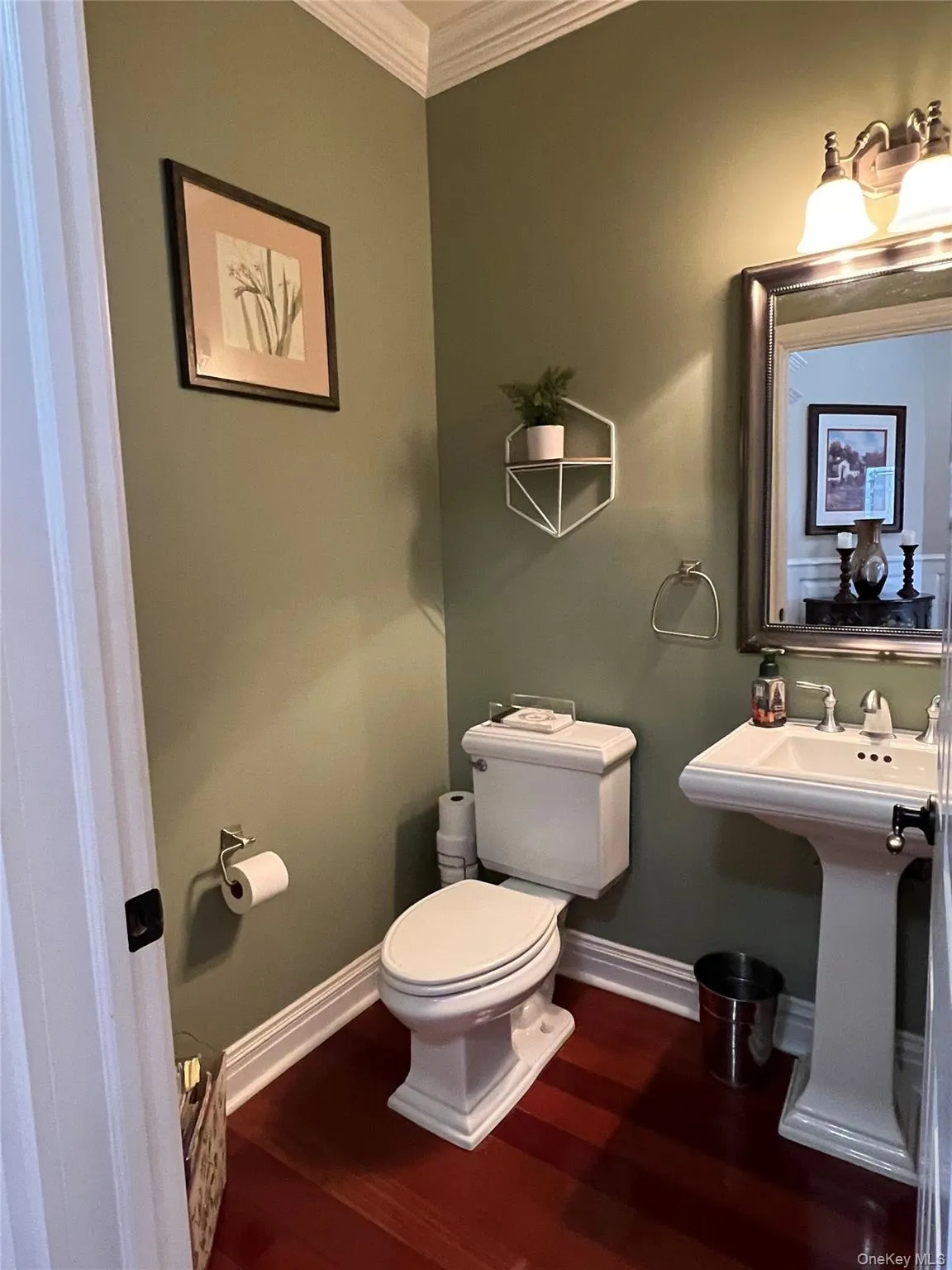 Half bath featuring ornamental molding and dark wood-style flooring Half bath featuring ornamental molding and dark wood-style flooring
