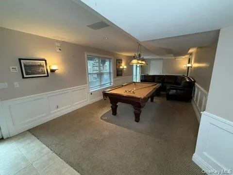 Playroom with a decorative wall, wainscoting, billiards table, and light tile patterned flooring Playroom with a decorative wall, wainscoting, billiards table, and light tile patterned flooring