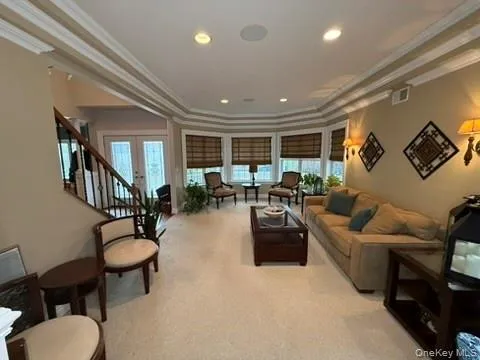 Living area with ornamental molding, a tray ceiling, french doors, light carpet, and recessed lighting Living area with ornamental molding, a tray ceiling, french doors, light carpet, and recessed lighting
