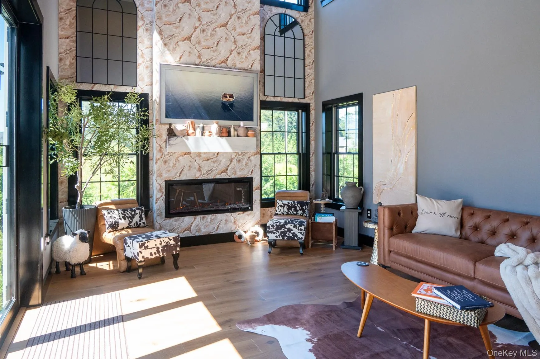 Living room with a glass covered fireplace, wood finished floors, and a high ceiling Living room with a glass covered fireplace, wood finished floors, and a high ceiling