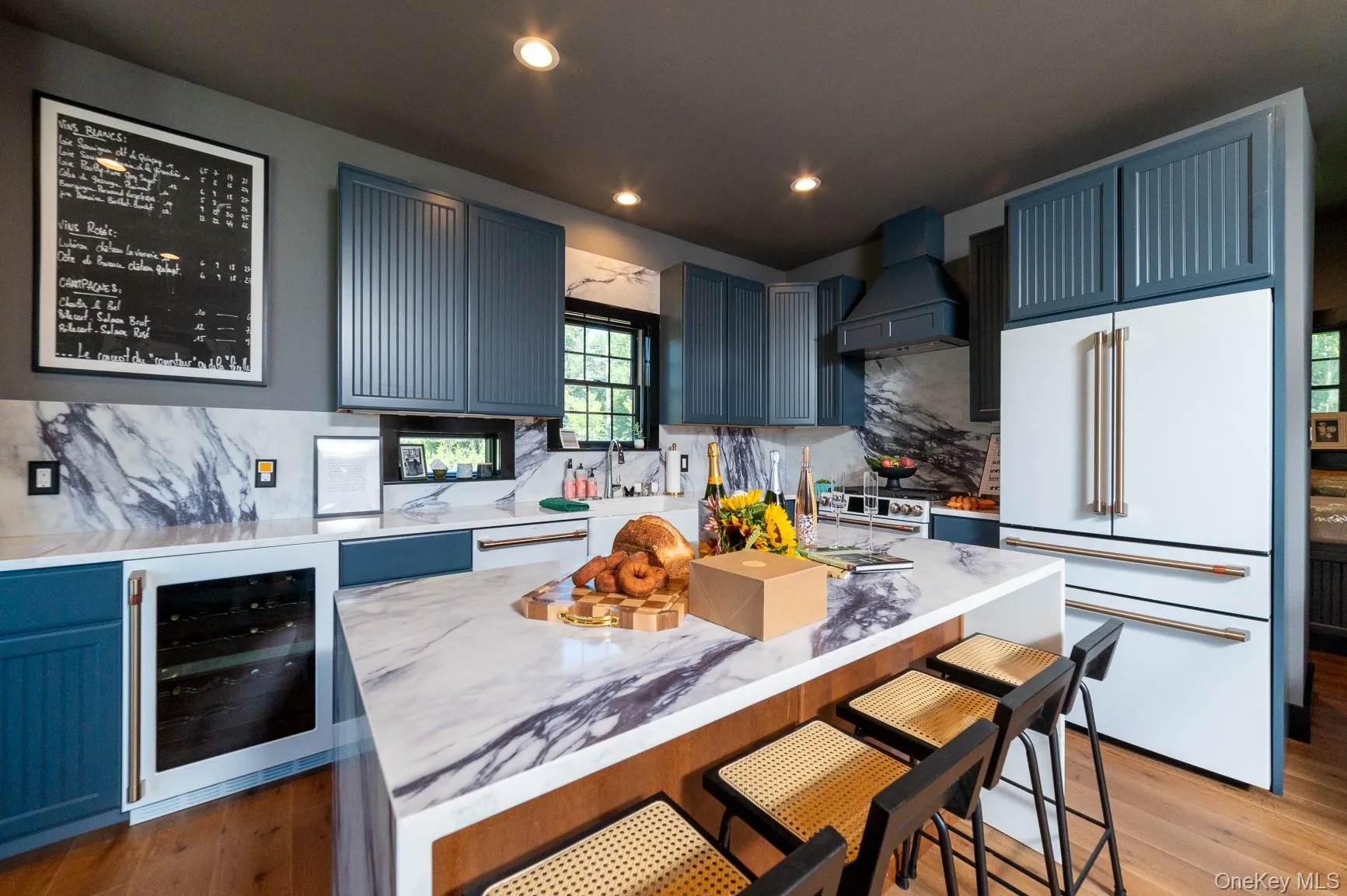 Kitchen with a breakfast bar area, white appliances, decorative backsplash, wine cooler, and a center island Kitchen with a breakfast bar area, white appliances, decorative backsplash, wine cooler, and a center island
