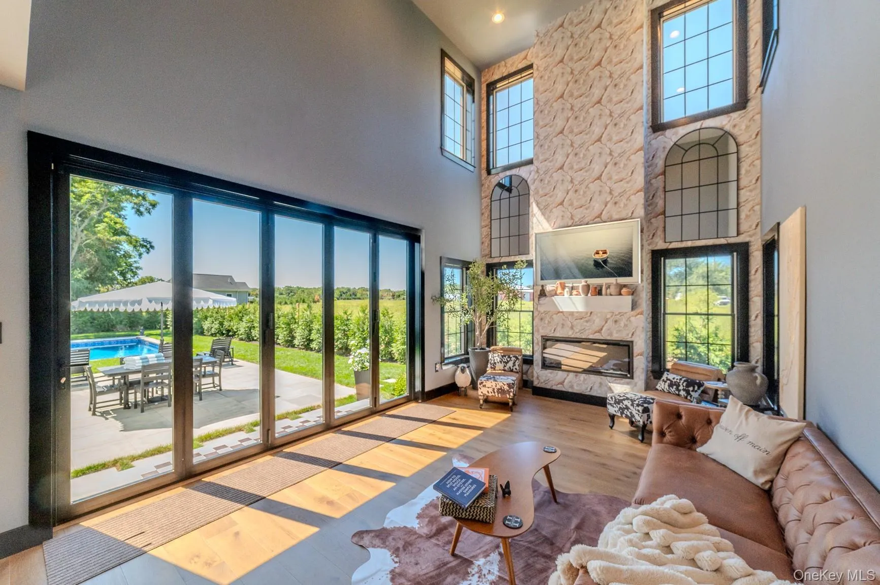 Living area with a fireplace, wood finished floors, and a high ceiling Living area with a fireplace, wood finished floors, and a high ceiling