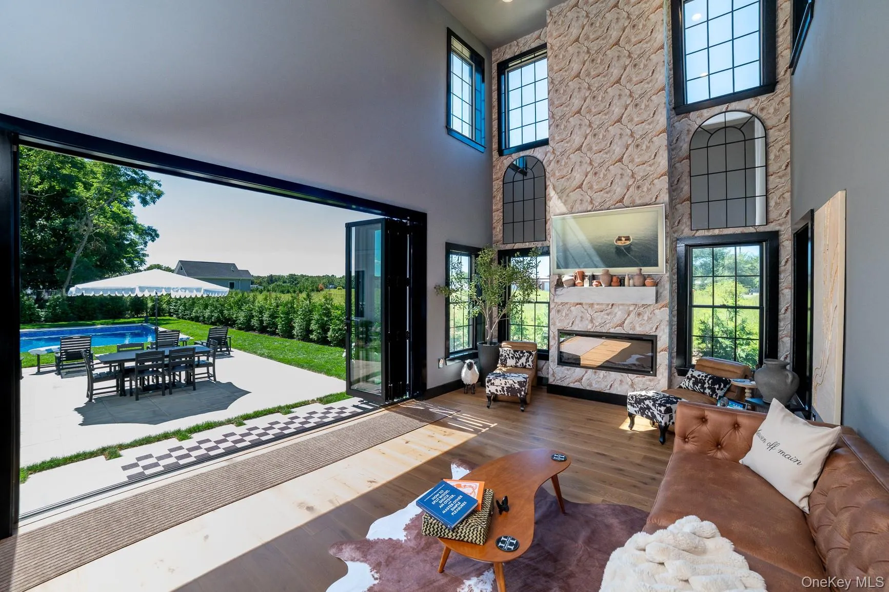 Furnished living room with a fireplace, wood finished floors, and a high ceiling Furnished living room with a fireplace, wood finished floors, and a high ceiling