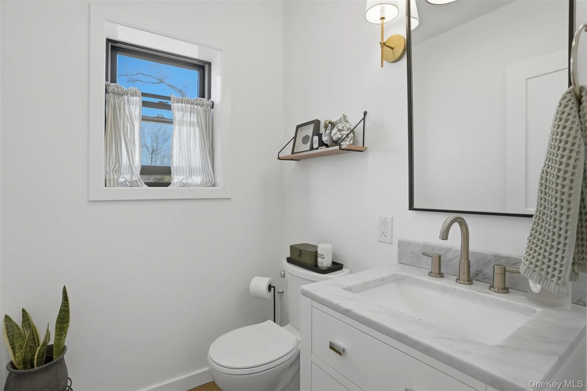 A modern, clean half bathroom sits at the end of the hallway ready for guests A modern, clean half bathroom sits at the end of the hallway ready for guests