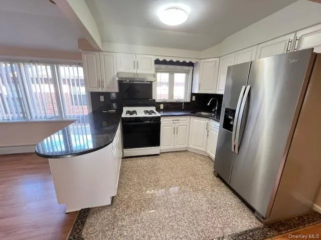 Kitchen featuring sink, stainless steel fridge with ice dispenser, white range oven, kitchen peninsula, and white cabinets Kitchen featuring sink, stainless steel fridge with ice dispenser, white range oven, kitchen peninsula, and white cabinets